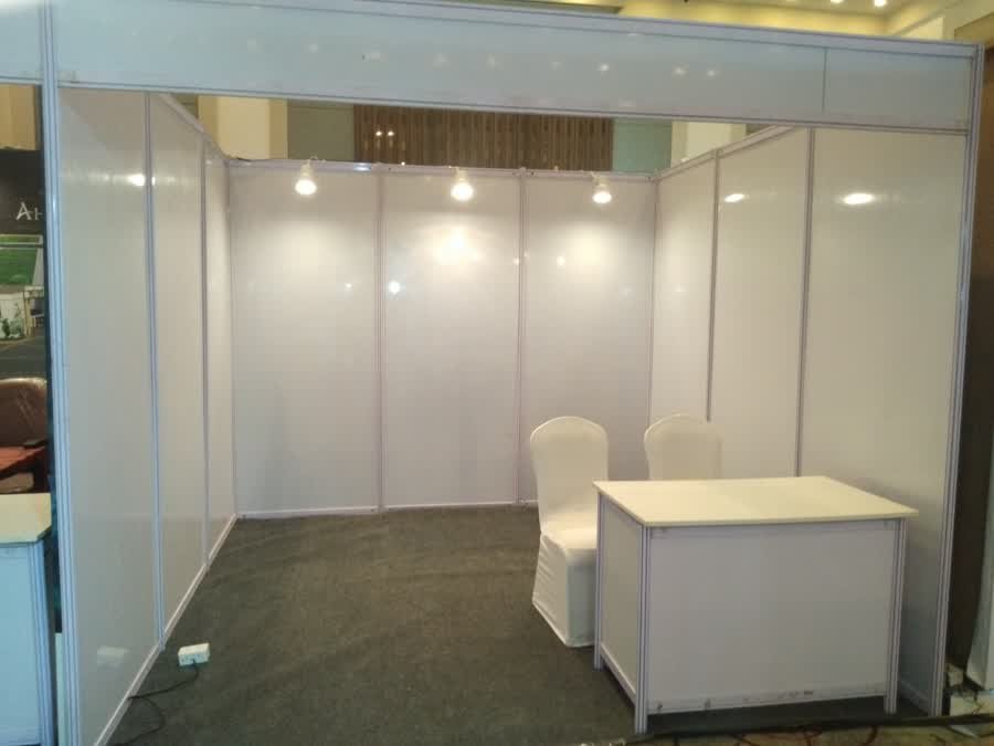 Example of what your stall will look like — 10x10 booth with white panel walls, lights, table and chair